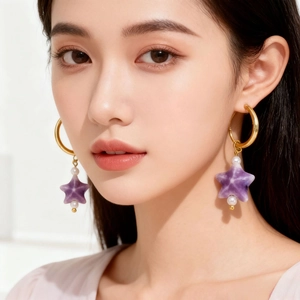 Elegant gold earrings with purple star pendant and pearls worn by a model in close-up