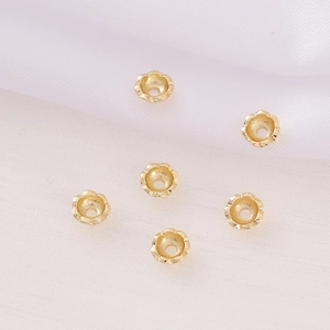 Gouden bloemvormige metalen kralenkapjes voor DIY-sieraden op witte zijden stof