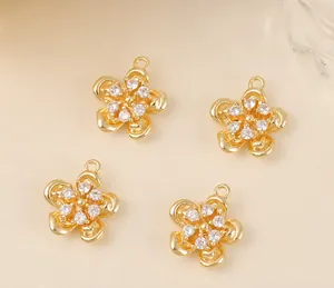 Détail de quatre pendentifs fleurs dorées avec centre en zircon pour bijoux artisanaux