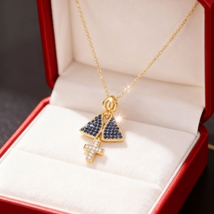 Detailaufnahme der goldenen Halskette mit blauen Steinen und Kreuz in einer Geschenkbox