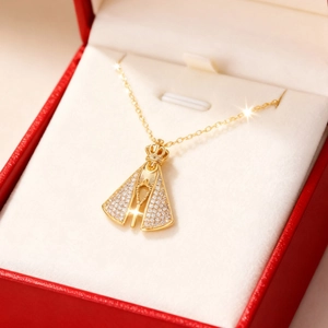 Detailansicht des goldenen Aparecida-Anhängers mit Krone und Kreuz auf rotem Schmuckkästchen