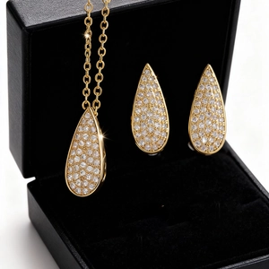 Vista macro de conjunto de collar y pendientes de gota dorados en caja de regalo