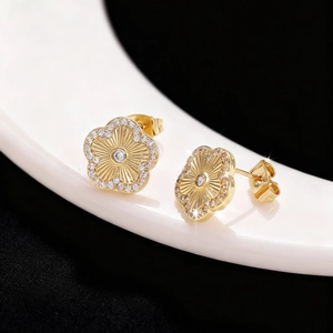 Vista de detalle de pendientes de flor dorada con cristal central y diamantes finos