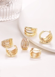 Detalle de pendientes huggie dorados multicapa con circonitas cúbicas micro-pave