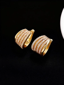 Primer plano de pendientes de aro dorados anchos con cuatro filas de circonitas brillantes