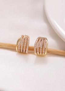 Primer plano de aretes de aro en C de oro con cinco filas de circonitas micro pavimentadas