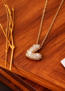 Λεπτομέρεια macro από χρυσό μενταγιόν γράμμα L με κρύσταλλα σε ξύλινη βάση