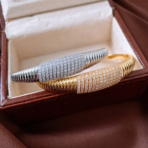 Vista macro dettagliata dei bracciali rigidi a corda in oro e argento con micro-pavè di zirconi
