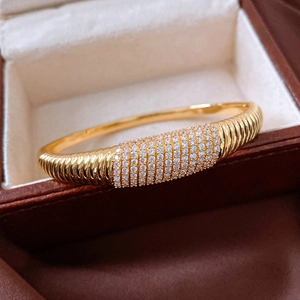 Dettaglio del bracciale ovale dorato a strisce con micro-pavé di zirconi bianchi