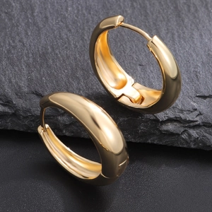 Boucles d'oreilles créoles dorées épaisses polies sur fond d'ardoise avec finition luxe