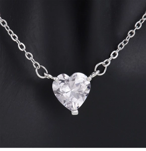 Detalle macro del colgante de corazón de circonita con cadena O de plata en negro
