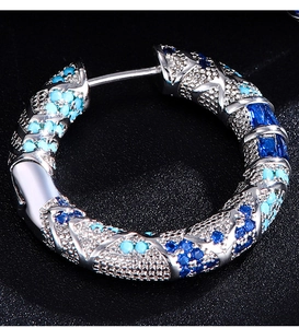 Dettaglio di orecchini a cerchio con pietre blu e turchesi incastonate a mano