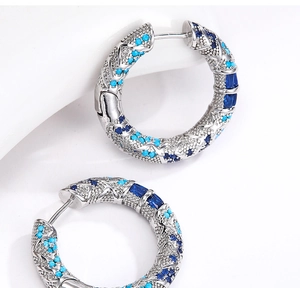 Dettaglio di orecchini a cerchio argento con perle turchesi e cristalli blu su metallo