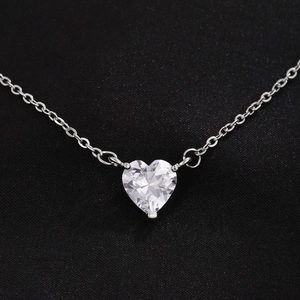 Elegante collar de corazón plateado con colgante de circón brillante en fondo negro