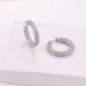 Dettaglio macro dei cerchi in argento con zirconi incastonati e texture a cuore