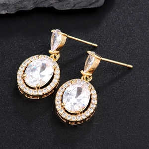 Elegante goldene Ohrhänger mit ovalem Zirkon und funkelnden Diamanten auf schwarzem Grund
