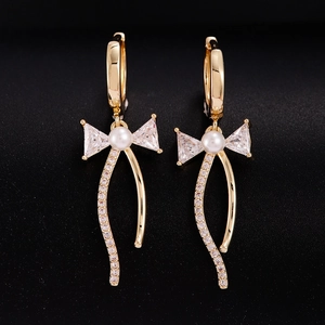 Boucles d'oreilles nœud dorées avec zircons, perle blanche et détails de glands pendants
