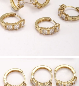 Detailed macro view of gold hoop earrings with square-cut cubic zirconia stones and beading
