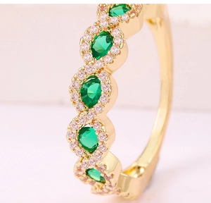 Foto macro de anillo dorado con gema verde esmeralda y halo de microcircones rosas