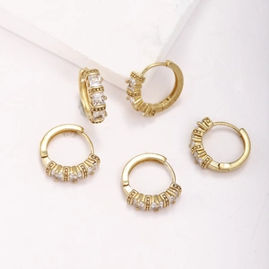 Set of five gold brass hoop earrings with square zircon stones on minimalist stone display