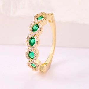 Elegante anillo ondulado dorado con cinco piedras verde esmeralda y pavé de circonitas