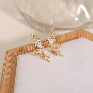 Macro shot of gold butterfly stud earrings with zircon wings and star pendant charms