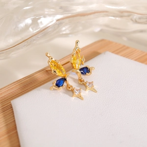 Detail of gold butterfly stud earrings with yellow blue gems and star charm