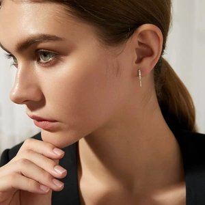 Close-up of minimalist gold zircon earrings worn by a model showing luxury craftsmanship