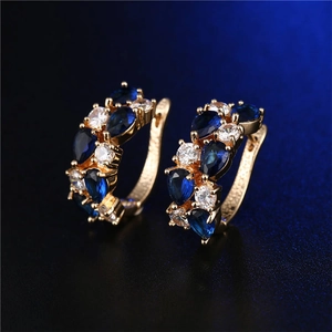 Dettaglio di orecchini a cerchio S925 con pietre blu a goccia e zirconi