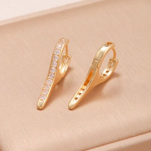 Macro shot of gold-plated huggie earrings with a line of clear cubic zirconia stones