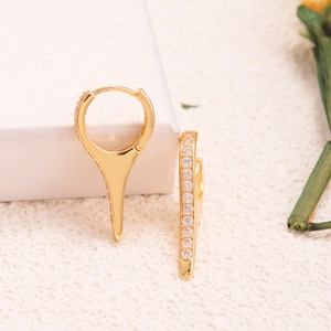 Macro detail of gold conical hoop earrings featuring micro-pave white zircon stones