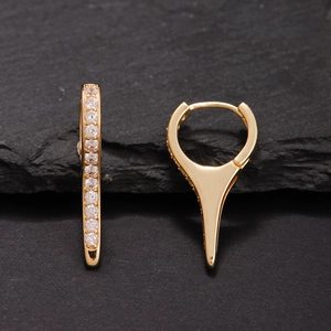 Detail of gold spike earrings with sparkling cubic zirconia on a dark textured background