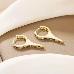 Macro shot of gold hoop earrings with multi-colored rainbow stones in a luxury setting