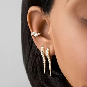 Macro view of gold-plated huggie earrings and ear cuff with shimmering white zircons