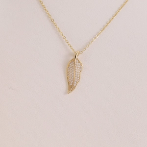 Dettaglio della collana con pendente a foglia e micro-pavé di zirconi in oro