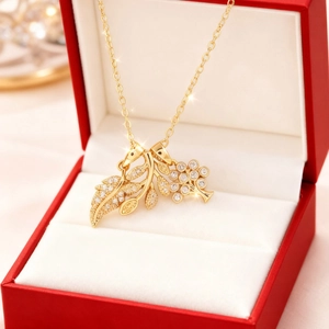 Dettaglio di una collana dorata con foglie e fiori e zirconi in una scatola regalo