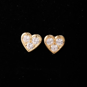 Vista macro di orecchini a cuore in oro con tre zirconi su sfondo di velluto nero