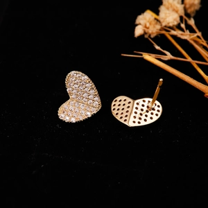 Dettaglio macro di orecchini a cuore placcati oro con zirconi e retro a nido d'ape