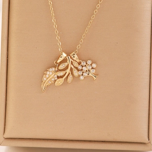 Set collana dorata con ciondoli a foglia e fiore in zirconi in una scatola per gioielli