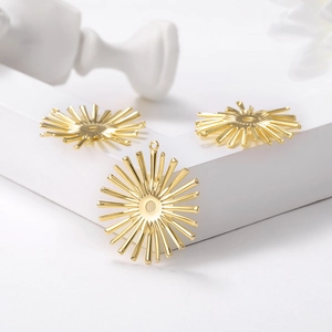 Polished gold sunburst metal charms for DIY jewelry making on white tiered display