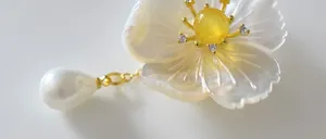 Macro view of handmade floral brooch featuring pearl shell petals and zircon details