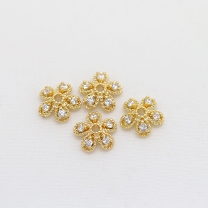 Macro detail of four gold-plated flower bead caps with inlaid cubic zirconia for DIY jewelry