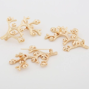 Detailweergave van drie gouden koraaltakbroches met matte textuur en speldsluiting