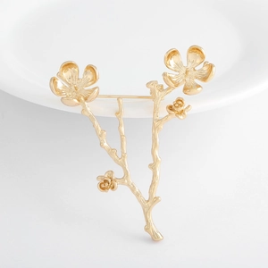 Detail of gold-plated plum blossom brooch with realistic branch texture and pin back