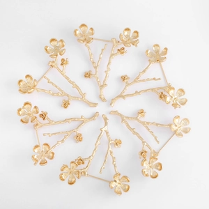 Detail of six gold-plated flower branch brooches with textured petals and buds