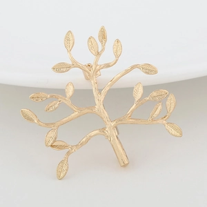 Macro detail of golden tree-shaped brooch with intricate branch and leaf textures