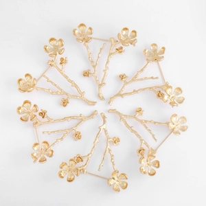 Artistic gold flower and branch brooches with matte metal texture in a circular layout