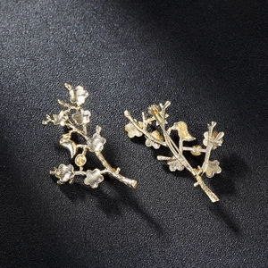 Pair of golden plum blossom bird brooches showing detailed back pin clasp and texture