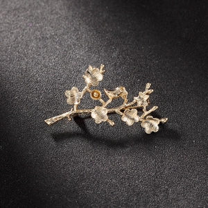 Golden plum blossom and magpie brooch with fine brushed metal texture on black background
