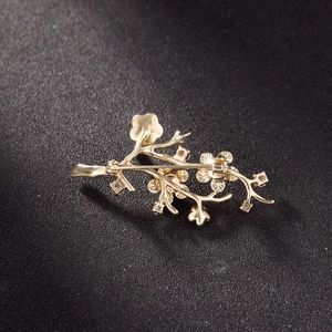Gouden tak bloem broche met zirkonia op een zwarte gestructureerde achtergrond